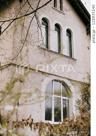 historic house with white and green roofs. house is surrounded by trees and it has lot of leaves. historic house with white and green roofs. house is surrounded by trees and it has lot of leaves. 128935540