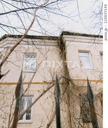historic house with white and green roofs. house is surrounded by trees and it has lot of leaves.  128935549