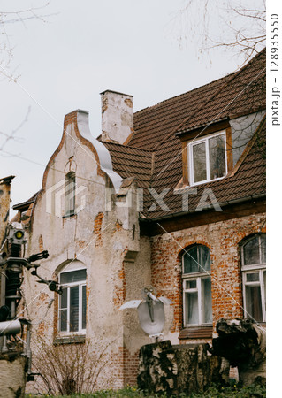 historic house with white and green roofs. house is surrounded by trees and it has lot of leaves.  128935550