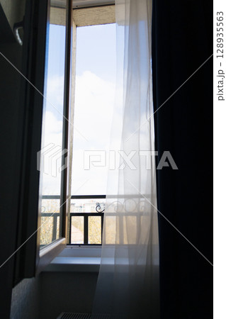 Skylight with sky view and balcony. The window offers a view of overcast sky with a few clouds. Skylight with sky view and balcony. The window offers a view of overcast sky with a few clouds. 128935563