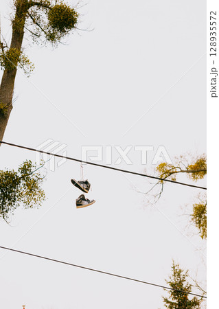 Graffiti from shoes. A pair of boots is hanging from a power line. Graffiti from shoes. A pair of boots is hanging from a power line. 128935572
