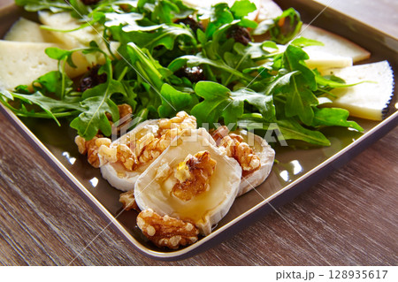 Arugula salad with goat cheese honey and nuts Arugula salad with goat cheese honey and nuts 128935617