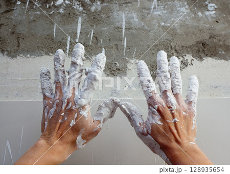 Astist plastering man hands with cracked plaster 128935654
