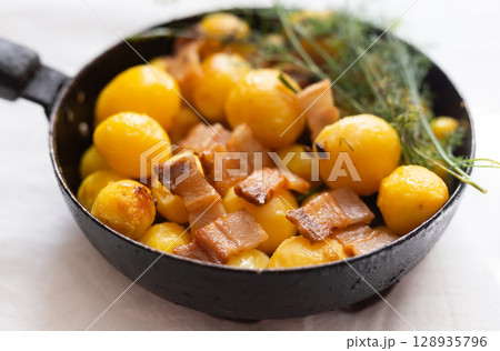 young potatoes with pork belly fried in frying pan young potatoes with pork belly fried in frying pan 128935796