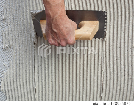 construction notched trowel with white cement 128935870