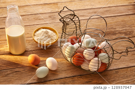 Eggs flour and milk in a vintage hen shape basket on wood 128937047