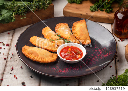 Fried empanadas served with spicy tomato dip Fried empanadas served with spicy tomato dip 128937219