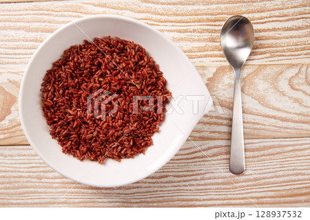 Red wild rice in a white plate over wood 128937532