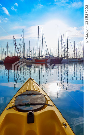 Kayak sailing in a marina port with boats 128937552