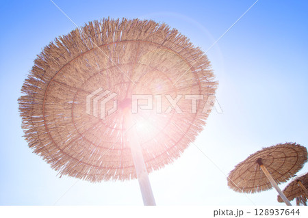 Hut sunroof umbrella on dried grass with lens flare 128937644