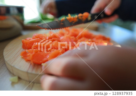 two child's hands cutting vegetables for salad close up 128937935