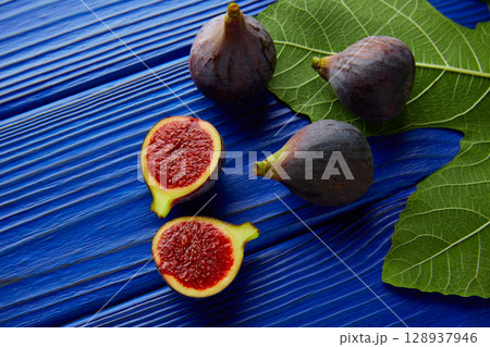 figs raw cutted fruits and fig tree leaves on blue figs raw cutted fruits and fig tree leaves on blue 128937946