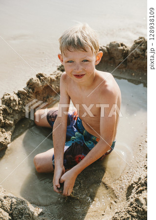Boy Enjoying Sand Play in Beach Water Boy Enjoying Sand Play in Beach Water 128938109