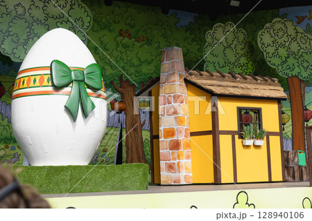 Easter decoration for children on stage with a yellow house and a large easter egg. Easter decoration for children on stage with a yellow house and a large easter egg. 128940106