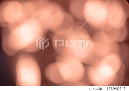 Abstract image featuring a warm bokeh effect with soft, glowing circular light orbs in golden. Dreamy atmosphere reminiscent of cozy evening lights or festive reflections, evoking a sense of warmth. 128940445