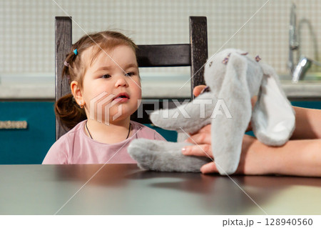 Young woman and little girl explore facial expressions and emotional bonding during a language learning session designed to improve speech development. 128940560