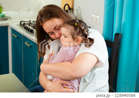 Child care provider embraces a preschool girl while building emotional intelligence and trust through physical affection and nurturing verbal interaction. Child care provider embraces a preschool girl while building emotional intelligence and trust through physical affection and nurturing verbal interaction. 128940566