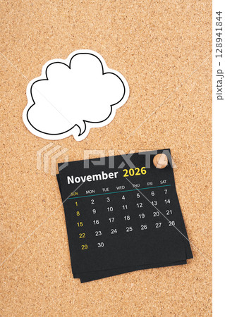 November 2026 Black calendar page and blank speech bubble with thumbtack on wooden board. November 2026 Black calendar page and blank speech bubble with thumbtack on wooden board. 128941844