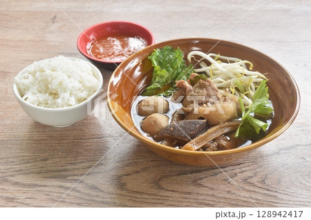 boiled braised beef meat and tendon couple organ in herb brown soup on bowl dipping spicy chili sauce eat couple with plain rice 128942417