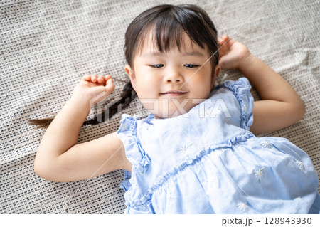 床に寝そべって笑う幼い女の子 床に寝そべって笑う幼い女の子 128943930
