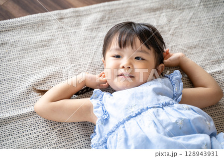 床に寝そべって笑う幼い女の子 床に寝そべって笑う幼い女の子 128943931