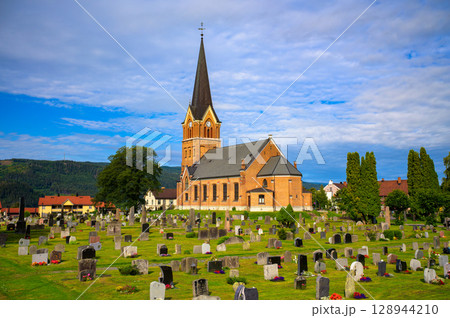Brick church with tall steeple and surrounding cemetery in Lillehammer, Norway 128944210