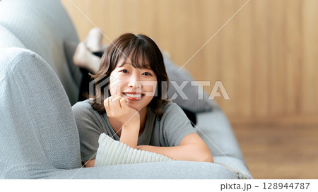 ソファに寝転ぶ笑顔の女性 ソファに寝転ぶ笑顔の女性 128944787