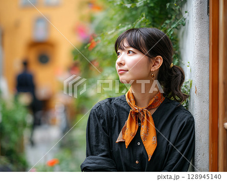 緑と花に囲まれた街角で佇む若い女性のポートレート 128945140