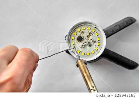 hands with a soldering iron solder radio components onto the board. 128945165