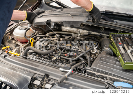 Car engine repair with open hood and toolkit during maintenance process Car engine repair with open hood and toolkit during maintenance process 128945213