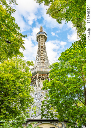 Petrin Lookout Tower rises above the lush trees in Prague, Czech Republic. Visitors can enjoy stunning views from the top, showcasing the city's skyline and natural beauty. Petrin Lookout Tower rises above the lush trees in Prague, Czech Republic. Visitors can enjoy stunning views from the top, showcasing the city's skyline and natural beauty. 128946304