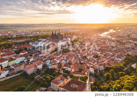 Prague Castle stands majestically against the vibrant sky at sunrise. The soft light illuminates the city, showcasing its beautiful architecture and historic charm as the day begins. 128946308