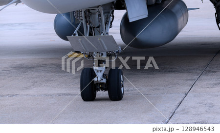 Close up of modern aircraft military fighter jet. Close up Jet parts such as landing gear engine nacelles weapon pods and cockpit with visible pilots showing defense technology and aircraft design. Close up of modern aircraft military fighter jet. Close up Jet parts such as landing gear engine nacelles weapon pods and cockpit with visible pilots showing defense technology and aircraft design. 128946543