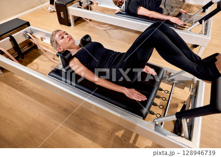 Fit individuals engaging in Pilates exercises on advanced training equipment in a studio 128946739