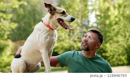 Man enjoying outdoor time with his dog in a park setting 128946793