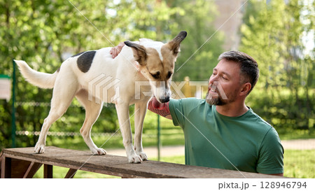 Man bonding with his dog outdoors on a sunny day in a park 128946794