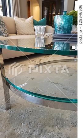 A glass coffee table with a blue vase on top of it 128946906