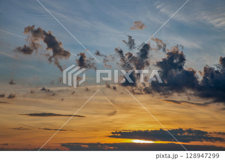 Dramatic sunset sky with scattered clouds Dramatic sunset sky with scattered clouds 128947299