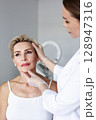 Facial plastic surgeon preparing patient for facelift surgery in medical clinic. Cosmetic face lifting procedure consultation, anti-aging operation for wrinkle correction and facial skin tightening 128947316