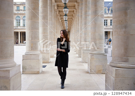 Elegant woman walking through stone colonnade in Paris 128947434