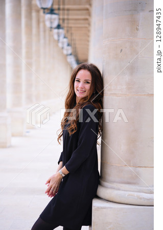 Smiling woman leaning on column in Paris Smiling woman leaning on column in Paris 128947435