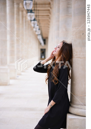 Relaxed woman leaning on column in Paris 128947448