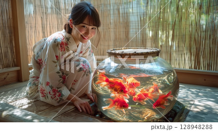 水槽を泳ぐ金魚と浴衣を着た女性 128948288