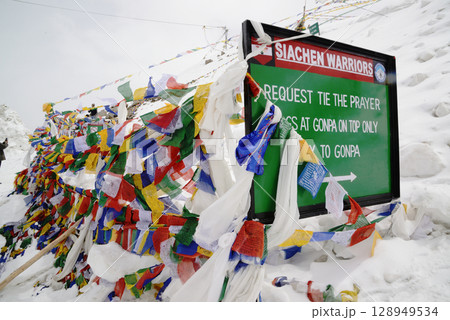 Height sign and Prayer flags at Khardung La. This pass is located in the Ladakh mountains north of Leh and connects the Indus and Shyok river valleys and is the highest motorable road in the world. 128949534