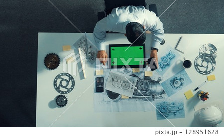 Top view of engineer look at mobile phone while working on tablet. Alimentation. 128951628
