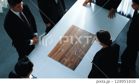 Top view of businesspeople putting jigsaw together at meeting room. Directorate. 128951810