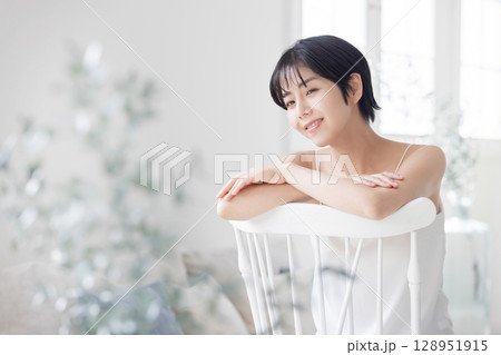 椅子を跨いで座るキャミソールの若い女性 128951915
