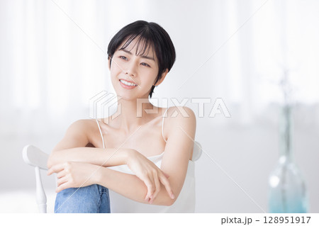 椅子に座るキャミソールの若い女性 128951917