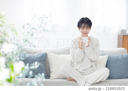 ソファーで目覚めのコーヒーを飲む女性 ソファーで目覚めのコーヒーを飲む女性 128952025