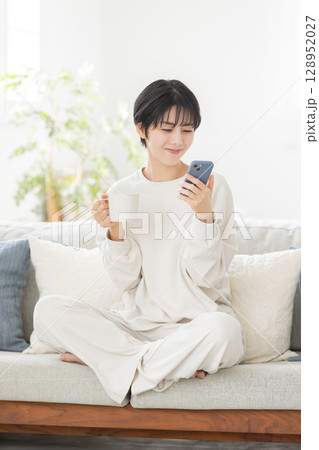パジャマでスマートフォンを操作する女性 128952027